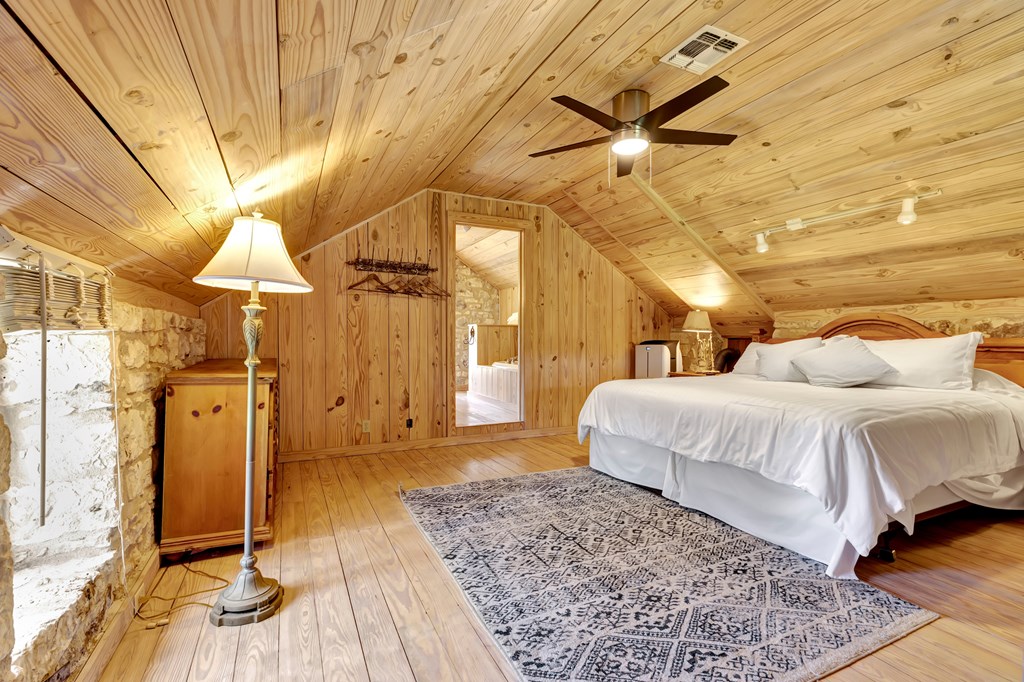 268 Marschall Creek Road Fredericksburg, TX 78624 - Photo 39 of 77 a spacious bedroom with a bed and wooden floor