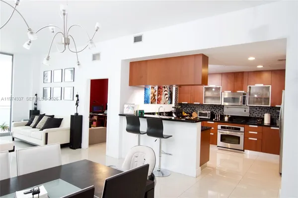 a kitchen with stainless steel appliances granite countertop a stove top oven a sink dishwasher a dining table and chairs with wooden floor