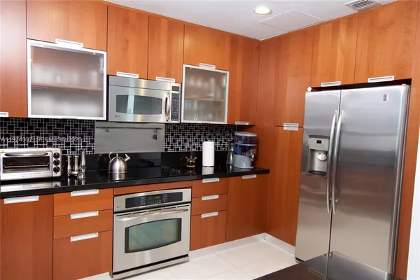 a kitchen with stainless steel appliances granite countertop a refrigerator a stove and a sink