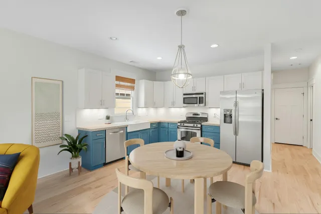 a kitchen with kitchen island a dining table chairs stainless steel appliances and cabinets