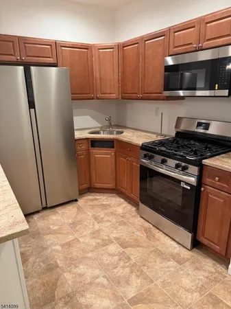 a kitchen with granite countertop a refrigerator and a stove top oven
