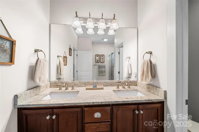 a bathroom with a granite countertop double vanity and a mirror