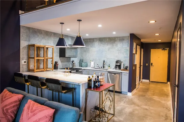 a kitchen with stainless steel appliances a sink a stove a refrigerator cabinets and living room view