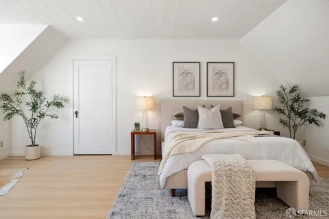 a spacious bedroom with a bed and a potted plant