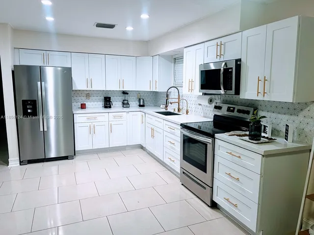 a kitchen with white cabinets stainless steel appliances and sink