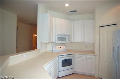 4708 Fairloop Run Lehigh Acres, FL 33973 - Photo 3 of 10 a kitchen with white cabinets and white appliances