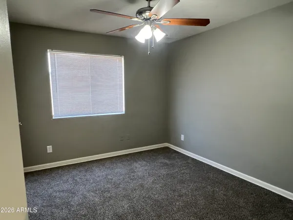 an empty room with a window and a fan