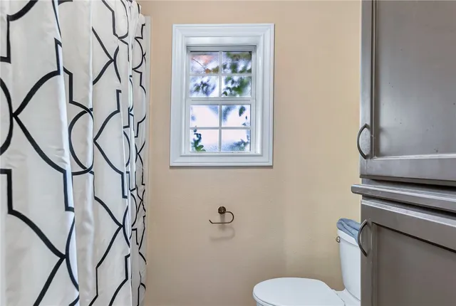 a bathroom with a toilet and a painting on the wall