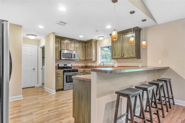 a kitchen with stainless steel appliances granite countertop a refrigerator a stove top oven and a sink