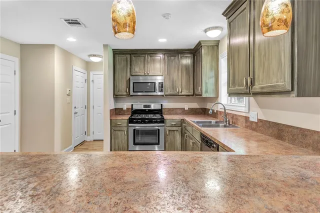 a kitchen with stainless steel appliances granite countertop a stove a sink and a refrigerator