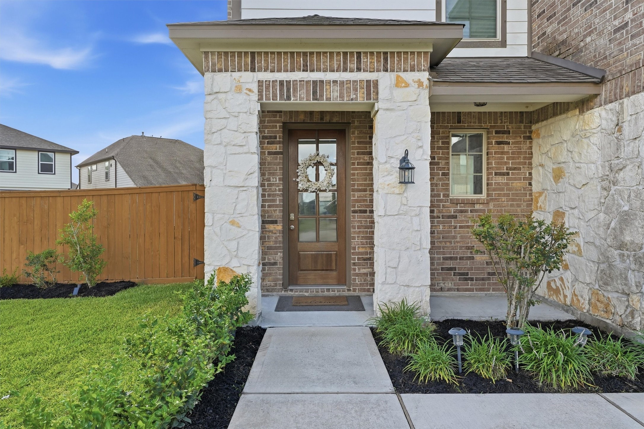 2130 Shellbark Way La Marque, TX 77568 - Photo 3 of 30 Inviting front entrance with a mix of brick and stone exterior. Wooden door and the pathway is bordered by neat landscaping. A wooden fence encloses the green lawn, adding privacy and charm.