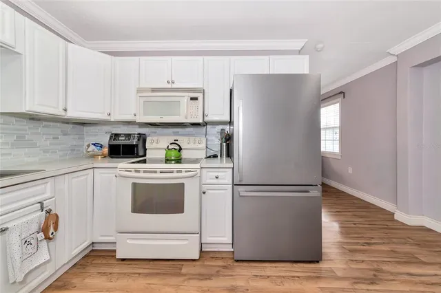 a kitchen with white cabinets and window