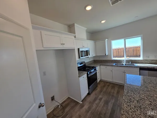 a kitchen with granite countertop a refrigerator a sink a stove a microwave and island