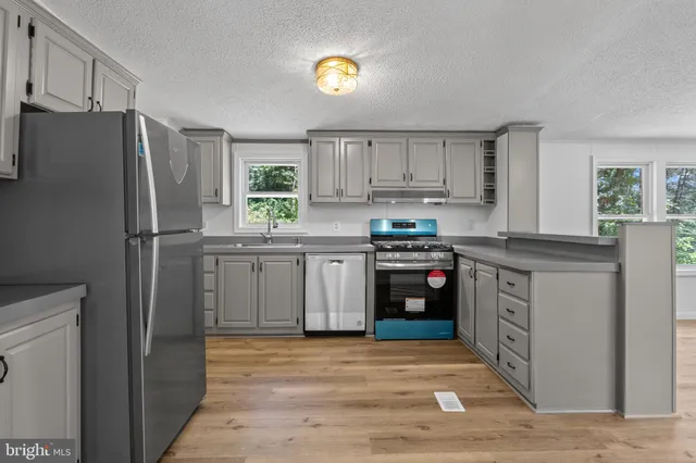 a kitchen with cabinets stainless steel appliances and a window