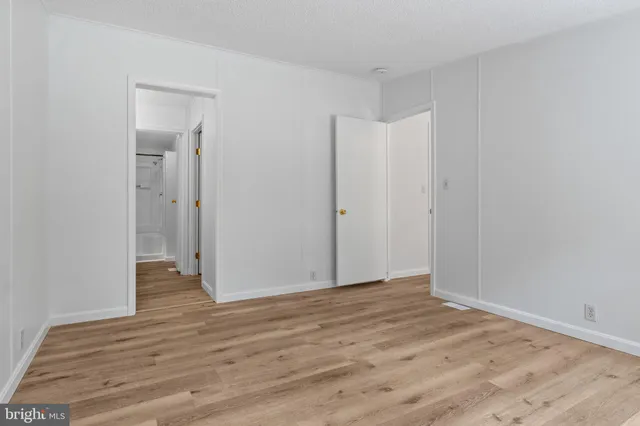 a view of an empty room with wooden floor and closet