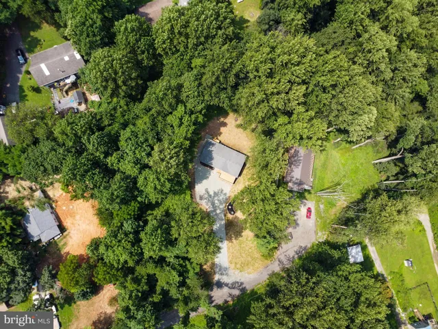 an aerial view of residential house with outdoor space and trees all around