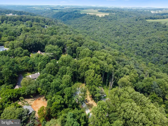 an aerial view of residential house with outdoor space and trees all around