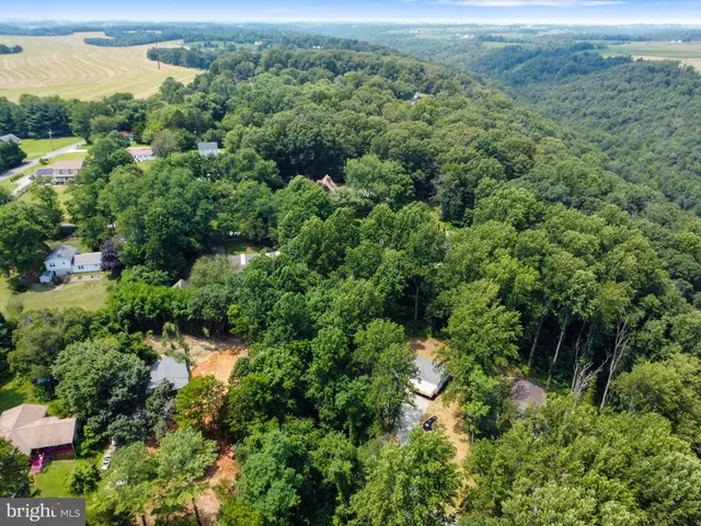 an aerial view of residential house with outdoor space and trees all around