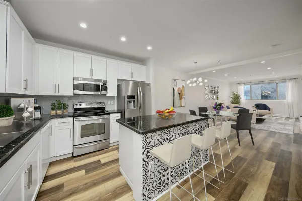 a kitchen with stainless steel appliances kitchen island granite countertop a stove a sink a microwave a dining table and chairs