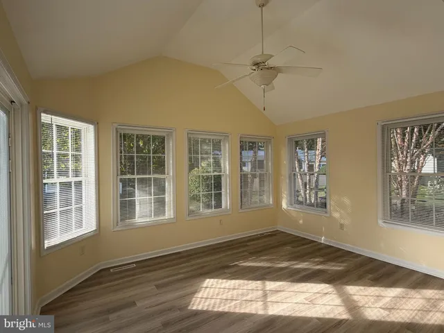 a view of an empty room with a window and wooden floor