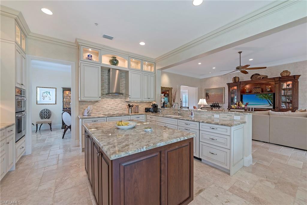 12014 Covent Garden Court, Unit 202 Naples, FL 34120 - Photo 49 of 50 Kitchen featuring a peninsula, light stone counters, a kitchen island, crown molding, and open floor plan