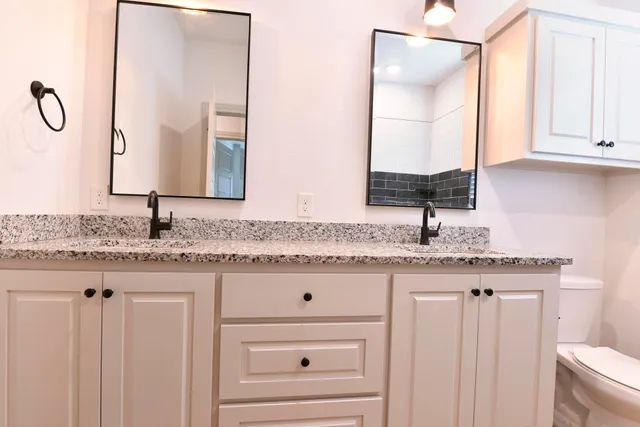 a bathroom with a granite countertop bathtub sink and toilet