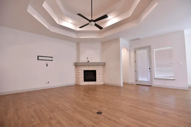 a view of a livingroom with a fireplace a ceiling fan and wooden floor