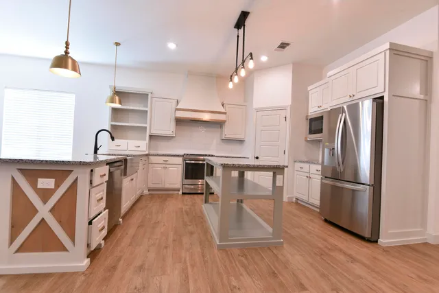 a kitchen with kitchen island wooden floors appliances and white cabinets