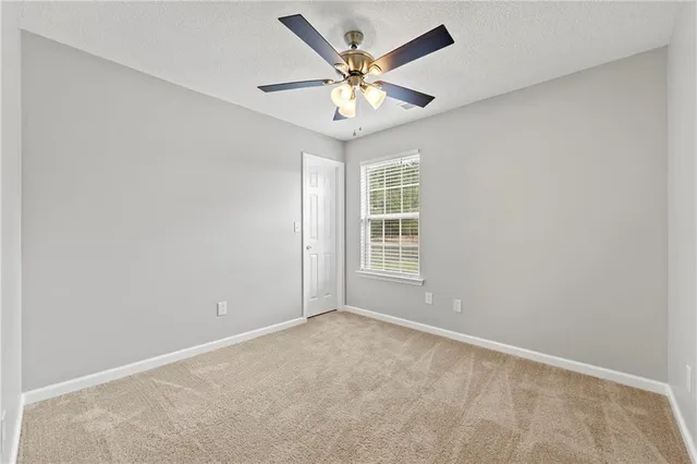 an empty room with a ceiling fan and window