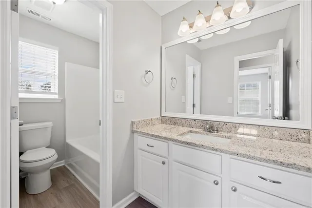 a bathroom with a granite countertop sink a toilet and a mirror