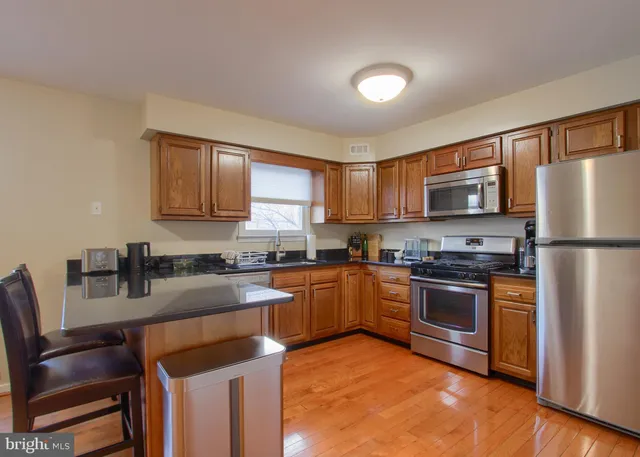 a kitchen with kitchen island granite countertop wooden cabinets stainless steel appliances a sink and a window