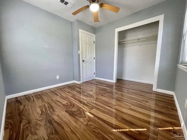 a view of a room with wooden floor and ceiling fan