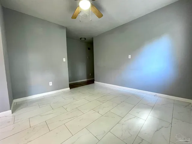 a view of an empty room and a chandelier fan