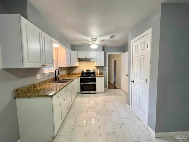 a large kitchen with stainless steel appliances granite countertop a stove a sink and a refrigerator