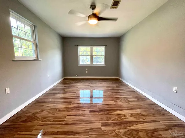 a view of empty room with wooden floor and fan