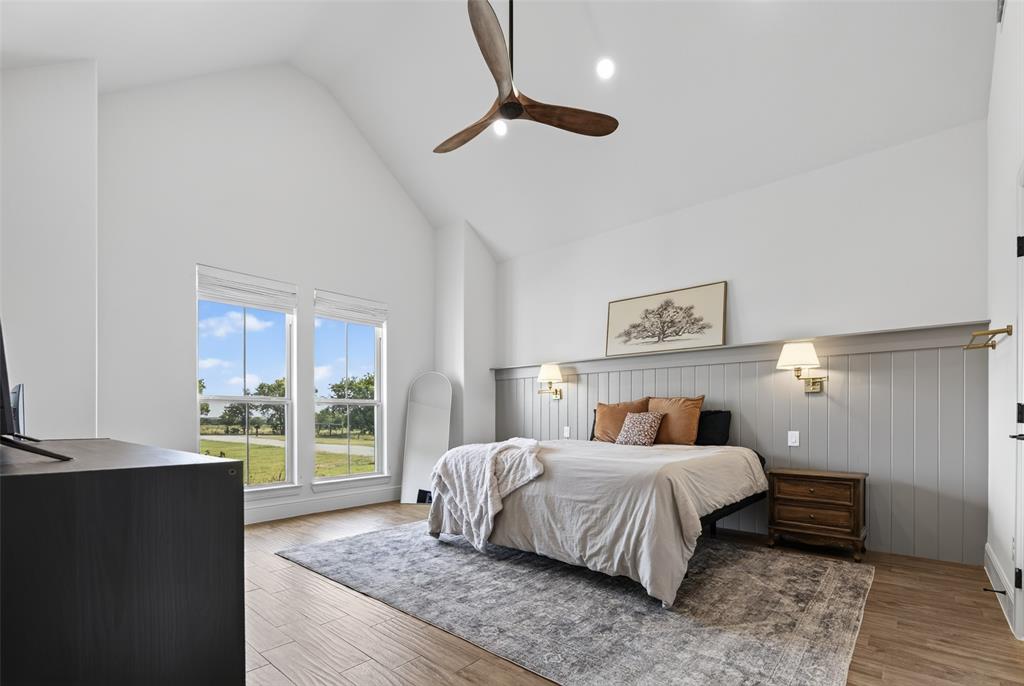 11032 Gregory Road Sanger, TX 76266 - Photo 25 of 40 Primary bedroom suite featuring vaulted ceilings with ceiling fan, wood-finish flooring, and expansive glass doors opening to outdoor landscape