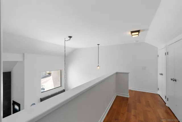 a view of an empty room with a window and kitchen view