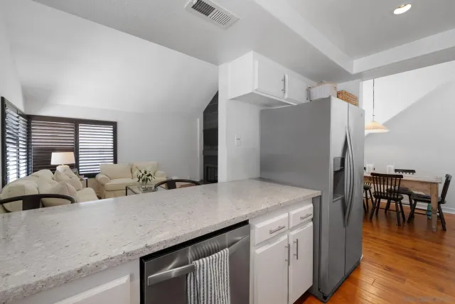 a kitchen with white cabinets and wooden floor