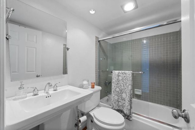 a bathroom with a bathtub shower sink vanity mirror and toilet