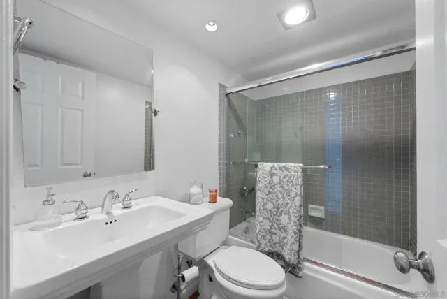 a bathroom with a bathtub shower sink vanity mirror and toilet