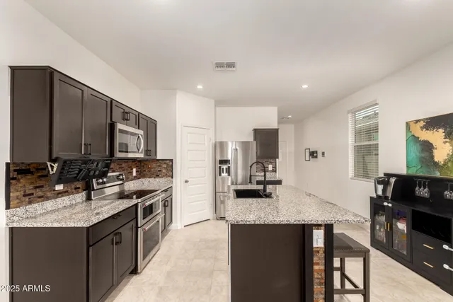 a kitchen with kitchen island granite countertop a sink stove and refrigerator