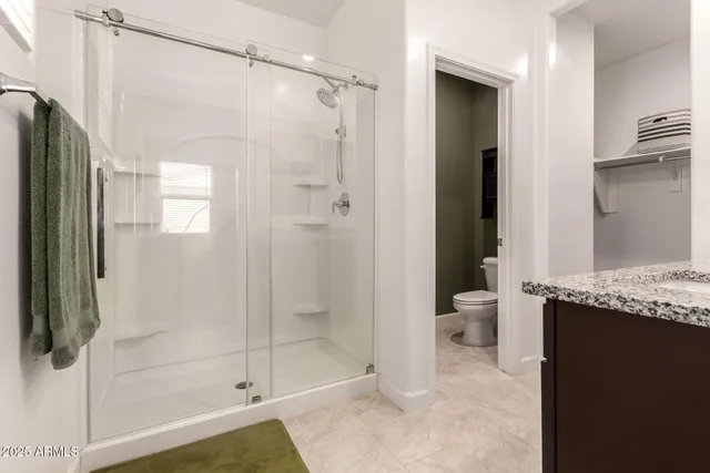 a bathroom with a granite countertop shower a mirror and a toilet