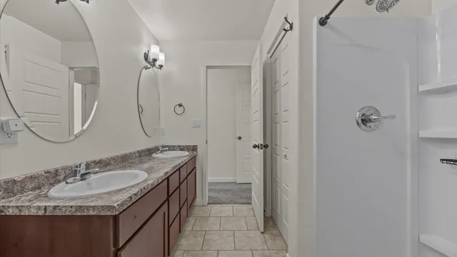 a bathroom with a granite countertop sink double vanity and a mirror