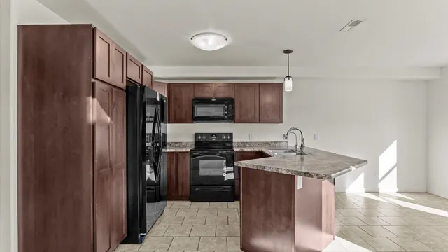 a kitchen with stainless steel appliances granite countertop a refrigerator a stove a sink and a microwave