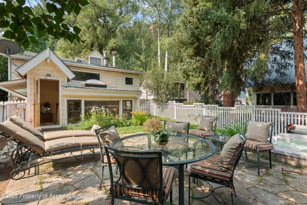 a view of a patio with a dining table and chairs with wooden fence