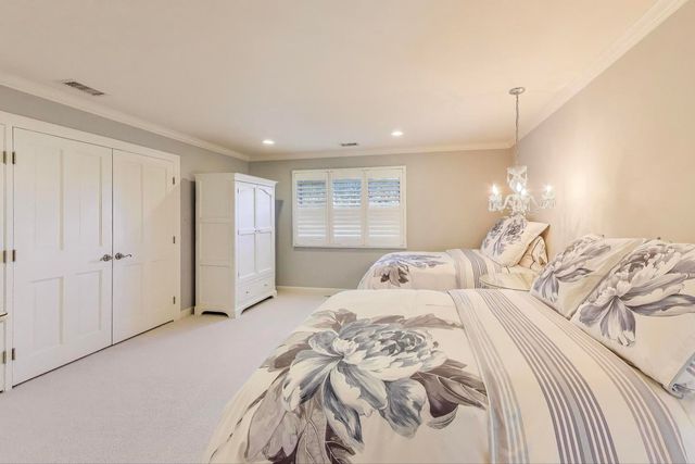 a spacious bedroom with two bed a lamp and a chandelier