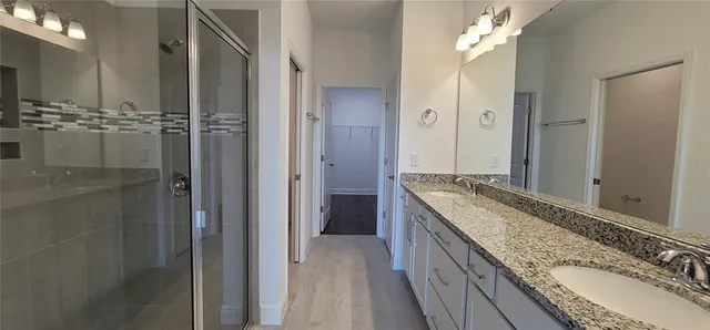 a bathroom with a granite countertop double vanity sink mirror and shower