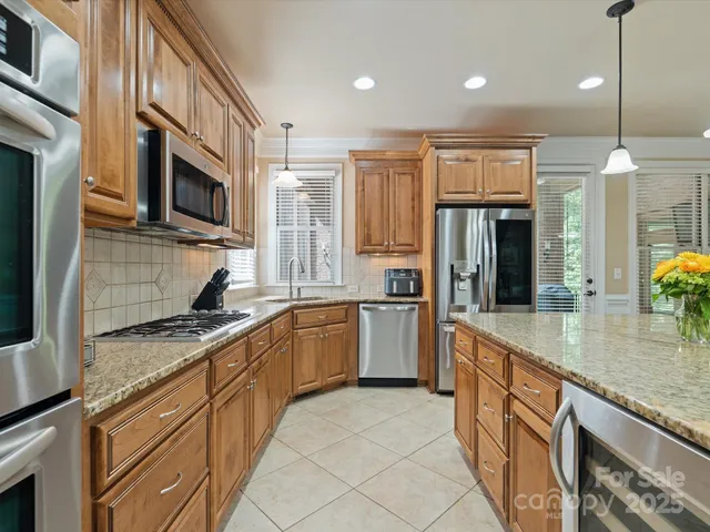a kitchen with stainless steel appliances granite countertop a sink a stove and a refrigerator
