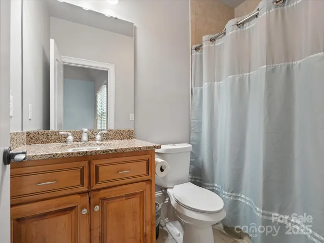 a bathroom with a granite countertop toilet sink and mirror