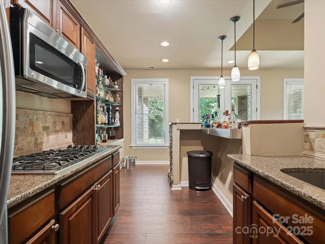 a kitchen with kitchen island granite countertop a stove and a wooden floor